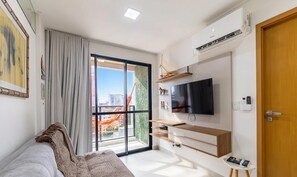 A modern bedroom with a large window, a flat-screen TV, and a sliding door to a balcony. - Apt in Condo w/ Pool & Sea View Sli1013 (Maceió)