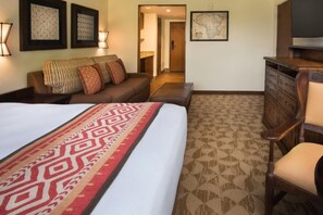 Een hotelkamer met een groot bed, een houten dressoir, een sofa en een kaart aan de muur.