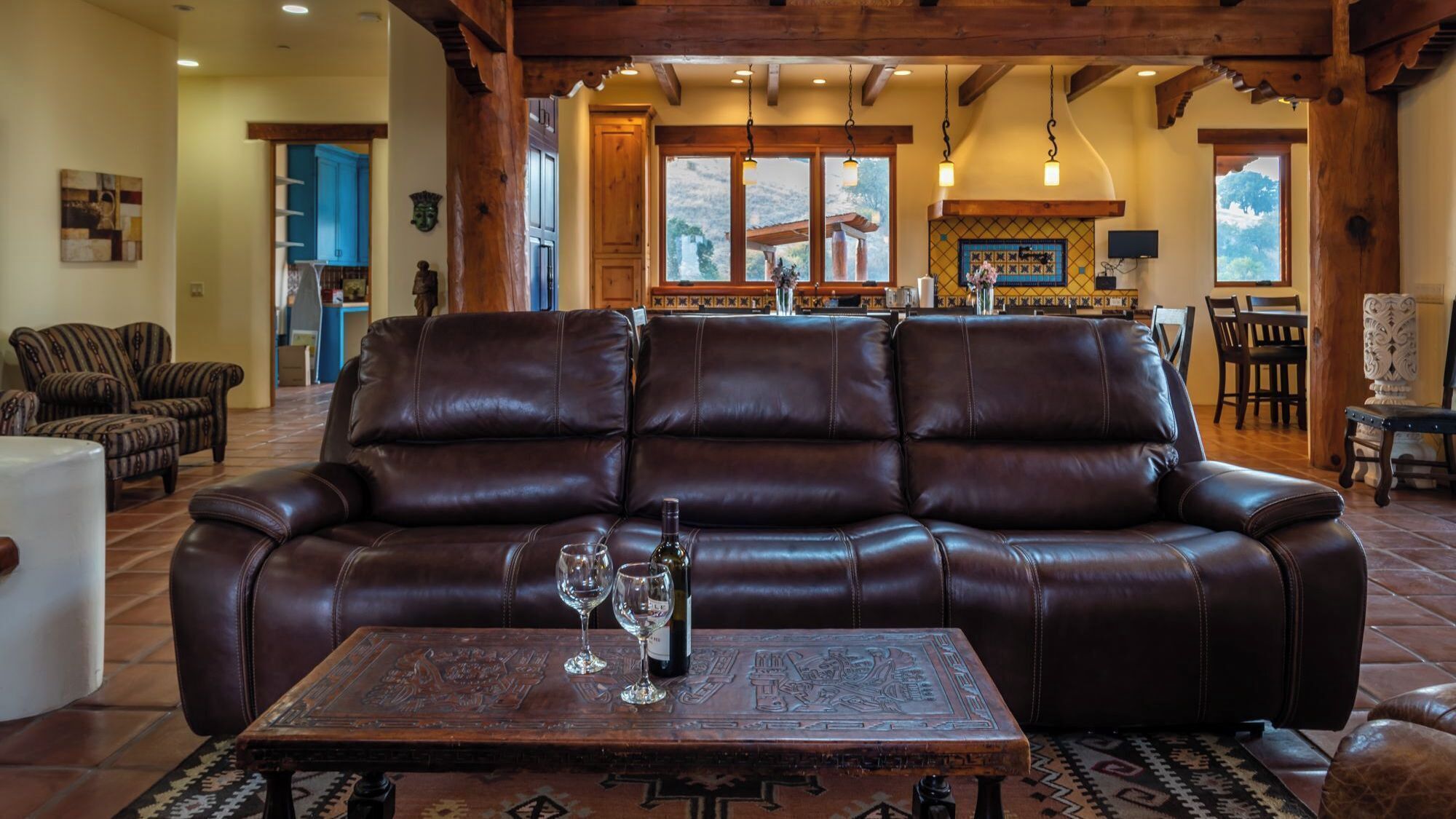 A leather sofa with a table in front, a kitchen in the background, and a dining area with chairs.