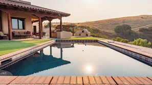 A swimming pool with a tiled edge, a patio area with outdoor furniture, and a view of a hilly landscape. - Renata's Retreat by Avantstay Private Pool + Game Room Starry Escape (Templeton)
