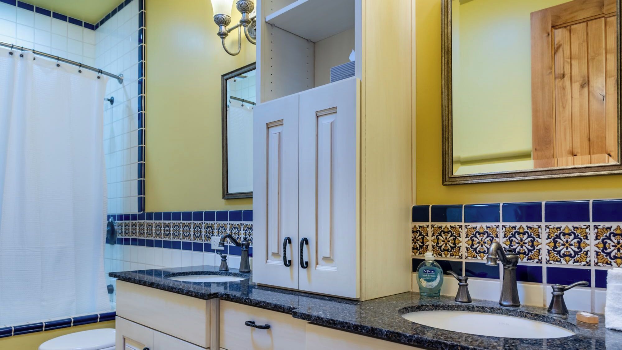 A bathroom with two sinks, a mirror, and a cabinet.