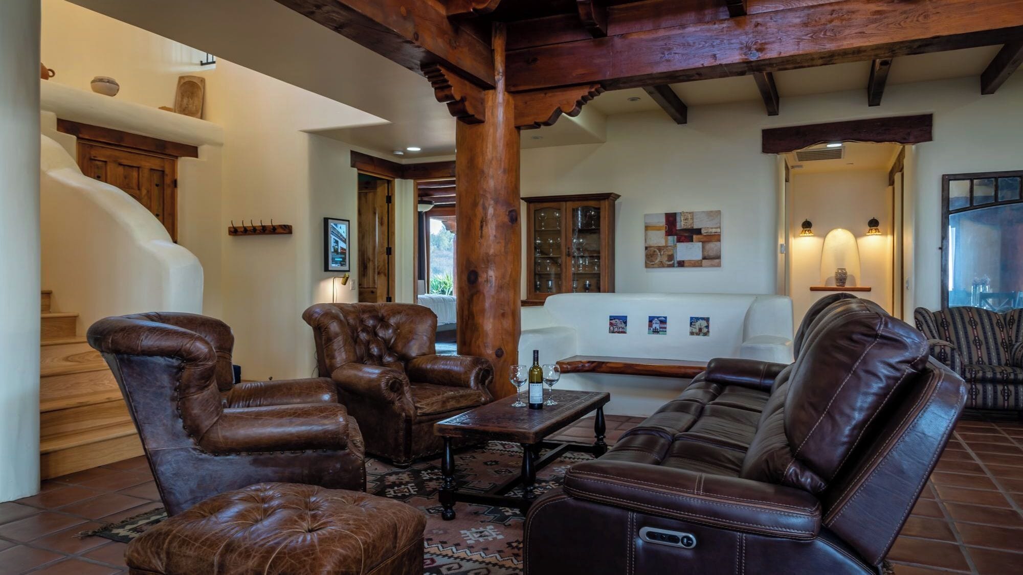 Amplia sala de estar con muebles de cuero, una escalera y vistas al exterior.