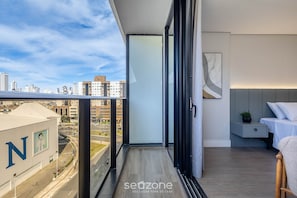 A balcony with a city view, a bed, a bedside table, and a wall-mounted artwork. - Apartment With Barbecue in Condo With Pool Tso0403 (Balneário Camboriú)