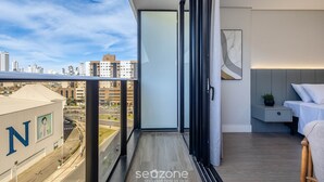 A balcony with a city view, a bed, a bedside table, and a wall-mounted artwork. - Apartment With Barbecue in Condo With Pool Tso0403 (Balneário Camboriú)