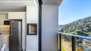 A modern kitchen with a built-in microwave, a stainless steel refrigerator, and a small mirror on the wall. - Apartment With Barbecue in Condo With Pool Tso0403 (Balneário Camboriú)
