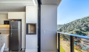 Eine moderne Küche mit integriertem Mikrowellenherd, einem Edelstahl-Kühlschrank und einem kleinen Spiegel an der Wand.