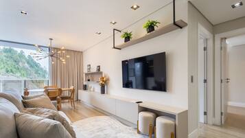 A modern living room with a sofa, TV, and a dining area with a table and chairs.