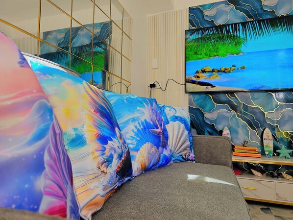 A modern living room with a sofa, a television, and artwork on the walls.