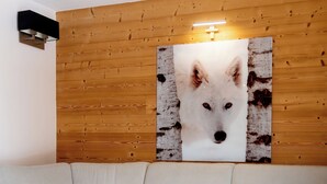 Uma sala de estar moderna com um sofá branco, uma mesa de centro redonda com uma revista, e uma grande imagem de uma raposa fixada na parede.