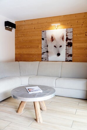 Ein modernes Wohnzimmer mit einem weißen Sofa, einem runden Couchtisch mit einer Zeitschrift und einem großen Wandbild von einem Fuchs.