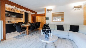 Um interior moderno com área de refeições, um sofá e vista para o exterior.