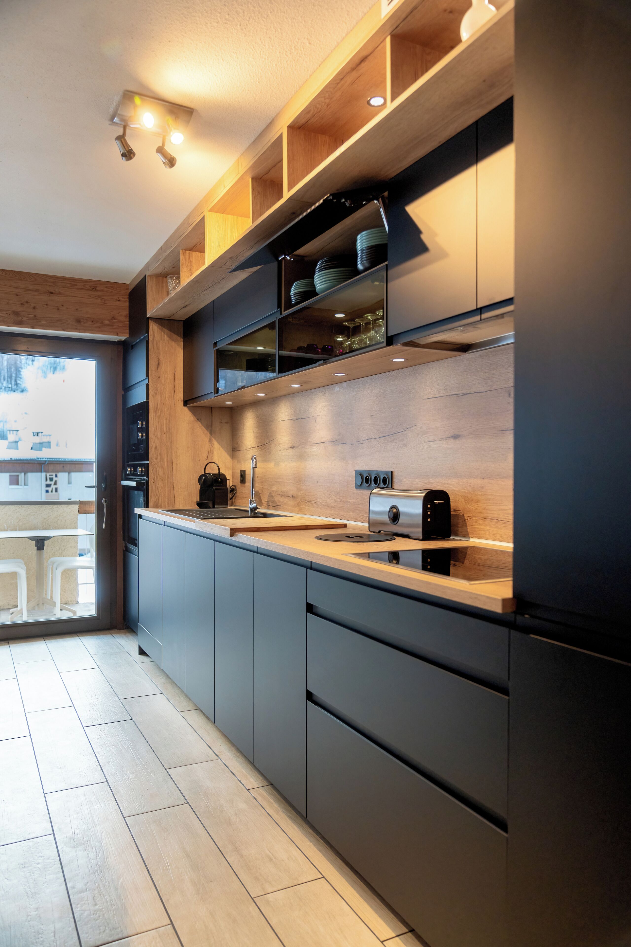 Eine moderne Küche mit Holzböden, einem eingebauten Backofen und einem Toaster.