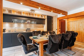 Eine moderne Küche mit Holzausstattung, einem Einbauofen und einem Essbereich mit Tisch für vier Personen.