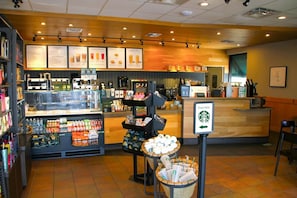 A coffee shop interior with a counter, menu boards, and a display of coffee cups. - Dune-Side Home w/ Loft & Dual Sound Views (Captiva)