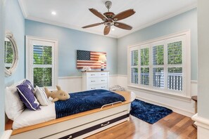 A bedroom with a bed, a ceiling fan, a dresser, and a window with a view of greenery. - Captiva Beachside Villa w/ Private Pool & Hot Tub (Captiva)