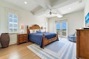 Un dormitorio con una cama grande, ventilador de techo y vistas al exterior.