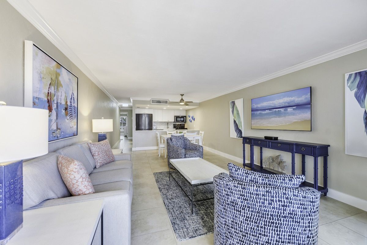 A modern living room with a sofa, a patterned armchair, a coffee table, and a TV.