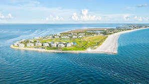 An aerial view of a coastal resort with beachfront properties, a marina, and a golf course.