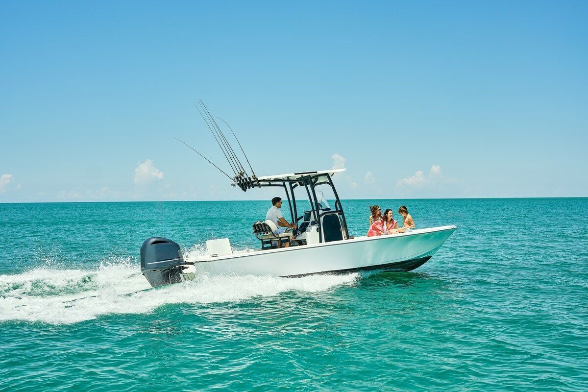 A small motorboat with a single motor and a canopy, moving through turquoise water.