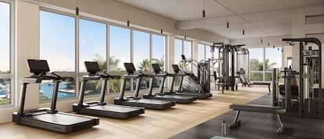 A gym with treadmills, dumbbells, and exercise equipment, large windows, and a view of the outdoors.