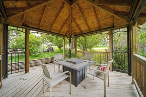 A covered outdoor area with a table and chairs, surrounded by a wooden deck and metal railing.
