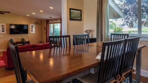 A dining area with a wooden table and chairs, a red sofa, and a television in the background. - Estrella Vineyard by Avantstay Vineyard Setting + Fire Pit Backyard Northern Paso Wine Country (San Miguel)