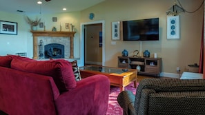 A living room with a fireplace, a flat-screen TV, and a red sofa. - Estrella Vineyard by Avantstay Vineyard Setting + Fire Pit Backyard Northern Paso Wine Country (San Miguel)