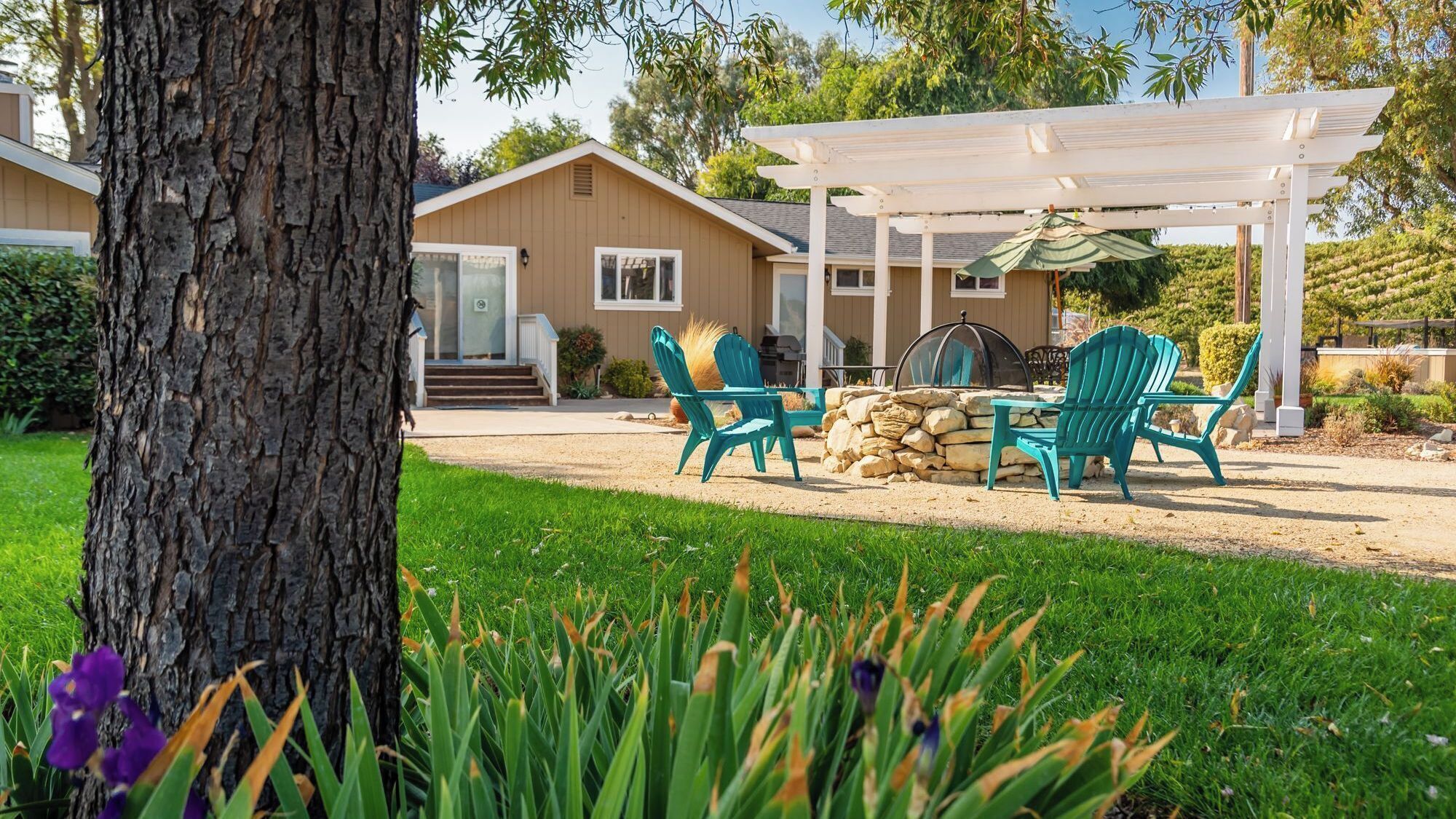 A house with a covered patio, outdoor seating, and a stone fireplace.