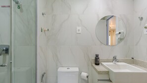 A modern bathroom with a glass shower enclosure, a toilet, a sink with a countertop, and a round mirror.