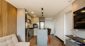 A modern kitchen with a central island, built-in appliances, and a seating area with a sofa and chair.