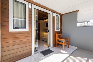 A wooden exterior with a sliding glass door leading to an interior space, a wooden bench, and a tiled floor. - Charming Cottage w/ Balcony Near the Beach Vil0002 (Penha)