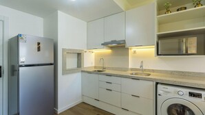 Una cocina moderna con refrigerador incorporado, microondas, lavadora y pileta.