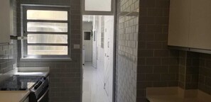 A kitchen with a stove, a window with blinds, and a tiled backsplash. - Room in a large apartment in Copacabana, with en-suite bathroom. (Rio de Janeiro)