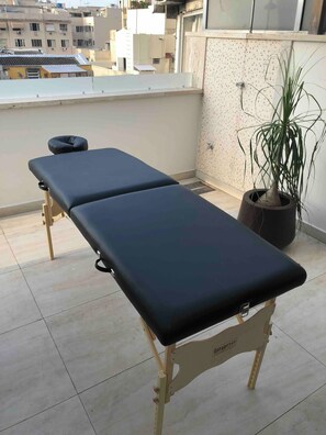 A balcony with two massage tables, a potted plant, and a tiled floor. - Room in a large apartment in Copacabana, with en-suite bathroom. (Rio de Janeiro)