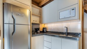 Cozinha moderna com frigorífico de aço inoxidável, máquina de café e micro-ondas embutido.