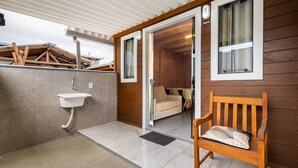 A wooden exterior wall, a bench, a door leading to a room, and a window.
