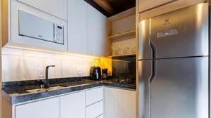 A modern kitchen with a built-in microwave, a stainless steel refrigerator, and a coffee maker.