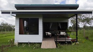 Uma casa moderna com varanda coberta, um espaço de estar ao ar livre e um gramado.