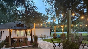 Un patio al aire libre con un espacio de estar techado, luces colgantes y un columpio.