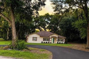 A single-story house with a front porch, surrounded by trees and a driveway. - Fireline's Ocala Retreat Near WEC, Springs Hot Tub! (Ocala City)