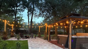 Un patio al aire libre con una chimenea, asientos e iluminación colgante.