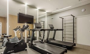 Ein Fitnessraum mit Laufbändern, einem Crosstrainer und einem Ergometer.