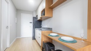A compact kitchen with a refrigerator, a microwave, and a wooden countertop. - Complete Studio in Perdizes Cep00428 (São Paulo)
