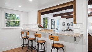 Eine Küche mit Barbereich, weiß gefliestem Fliesenspiegel und Holzküchenstühlen.