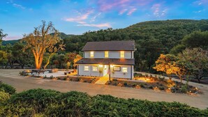 A two-story house with a well-lit entrance and a welcoming sign. - 8 Mile House by Avantstay Historic 1877 Ranch + Party Barn Wine Country (Santa Margarita)