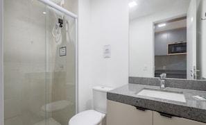 A modern bathroom with a glass shower enclosure, a toilet, and a granite countertop with a sink. - Studio in Building c/ Balcony in Perdizes Cep00427 (São Paulo)