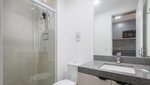 A modern bathroom with a glass shower enclosure, a toilet, and a granite countertop with a sink. - Studio in Building c/ Balcony in Perdizes Cep00427 (São Paulo)