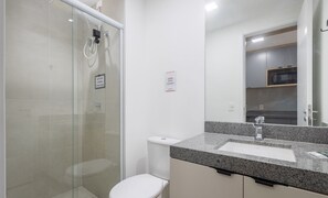 Ein modernes Badezimmer mit Duschkabine aus Glas, Toilette und Waschbecken auf einer Granitplatte.
