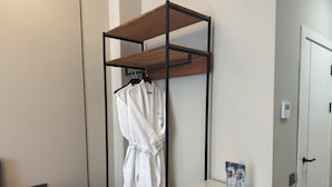 A hotel room with a wooden shelf unit, a white table, a small cabinet, and a door with a handle. - Wind Rose hotel (Almaty)