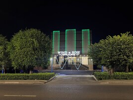 Entrada de hotel con un letrero que dice 'WIND ROSS QONAGOUI HOTEL' y un diseño moderno con luces verdes verticales.